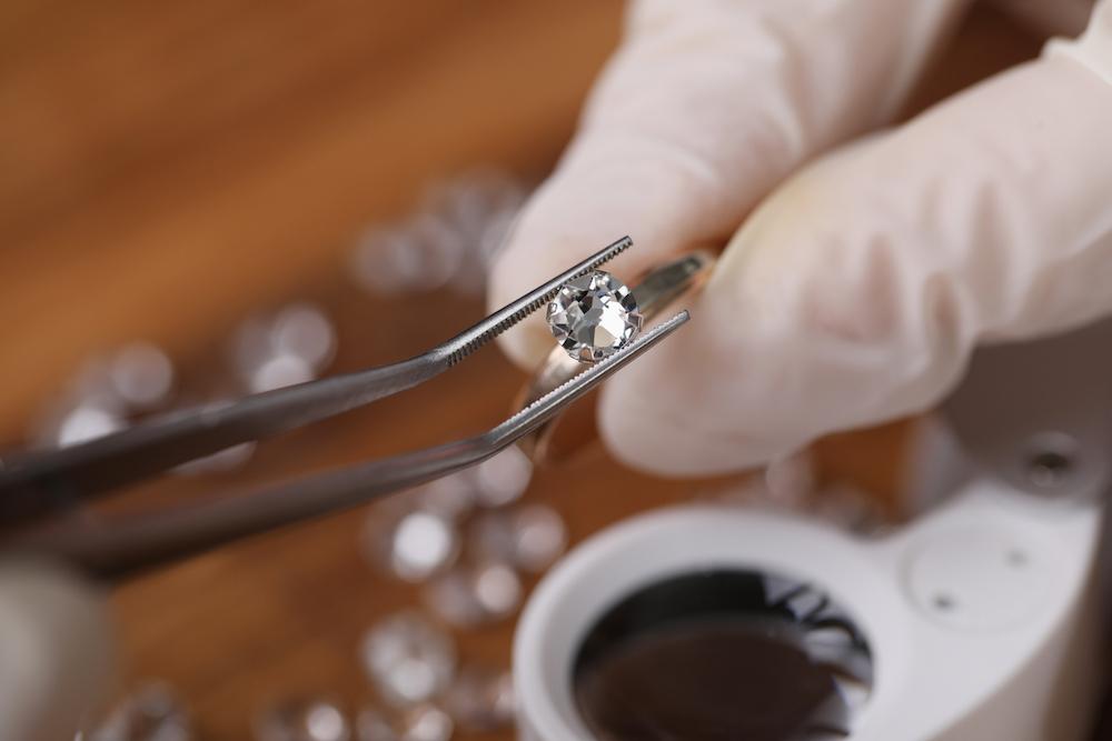 Tweezers and a gloved hand holding a ring. 