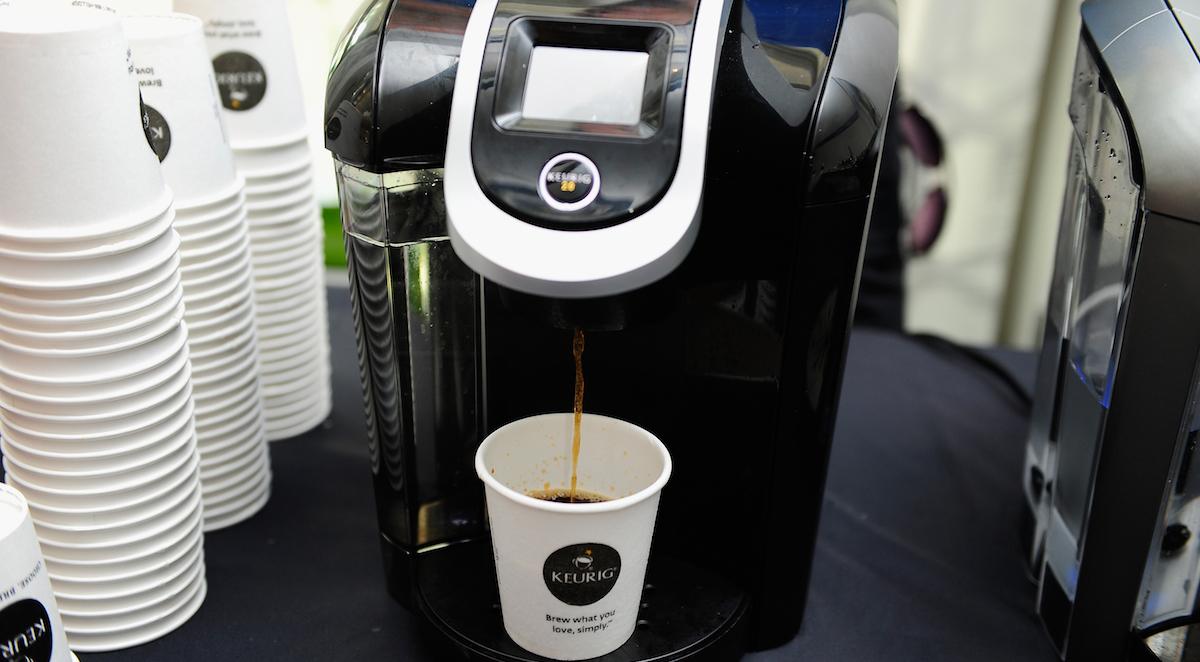 Coffee is dispensed from a Keurig coffee machine into a paper cup